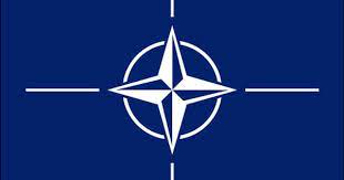 The flag of the north atlantic treaty organization (nato) consists of a dark blue field charged with a white compass rose emblem, with four white lines radiating from the four cardinal directions. Nato Flag The North Atlantic Treaty Organization Nato Flag Flags Of The World Flag