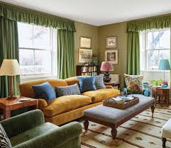 A resting place for your tired feet and a makeshift coffee table. Rita Konig Living Room Mustard Yellow Corduroy Sofa Green Curtains Ottoman Coffee Table Country House England Farmhouse Elle Decor June 2019 Katie Considers