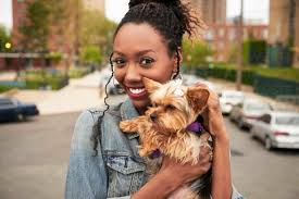 Black woman holding dog in city stock photo