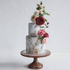 The simple strand of deep green leaves pops against white tiers, making it a good choice for couples who want to serve a simple rustic wedding cake. Marbled Cake With Flowers On 16 Inch Wood Cake Stand I Sarah S Stands