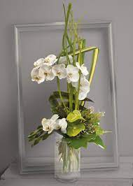 Composition florale harmonieuse de primevères, pensées, chatons de décoration surprenante: Celeste Bouquet En Hauteur D Orchidees Phalaenopsis Blanches Et Anthuriums Verts Avec Travail De Feui Blumenarrangements Beileid Blumen Modernes Blumenmuster