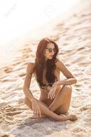 Nude Beautiful Woman On The Nudist Beach. Lady With Nude Perfect Body  Sitting On Sand Near Sea. Gorgeous Mixed Race Caucasian Asian Girl Posing  In Sunglasses On Travel Vacation Holidays Naked Outdoors