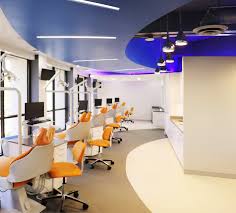This dental office interior design incorporates shiny, weathered silver metal on chairs, benches, and the reception desk. Modern Greencurve