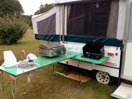 An angled double sink at the kitchen area with a refrigerator and a three burner. Pin On Rv Camper Hacks Ideas