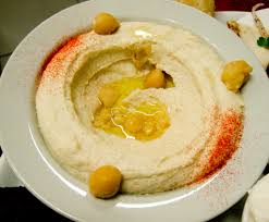 A dish of creamy hommus, garnished with paprika and a few chickpeas