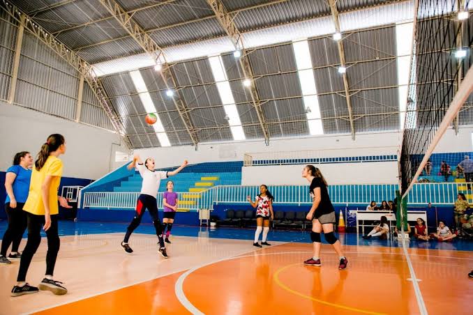 Grupo de garotas jogando vôlei em uma quadra coberta em Itupeva, participantes de uma das 19 modalidades gratuitas oferecidas pelas escolinhas de esporte da cidade.