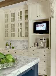 Glass Front Ivory Kitchen Cabinets Are Mounted Above Ivory Shaker Cabinets Topped With A Gray And White Marb Ivory Kitchen Ivory Kitchen Cabinets Tv In Kitchen