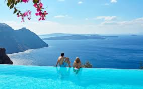 A Couple Enjoy The Hotel Infinity Pool The Sea Views At San Antonio Luxury Hotel In Santorini Santorini Hotels Infinity Pool Pool