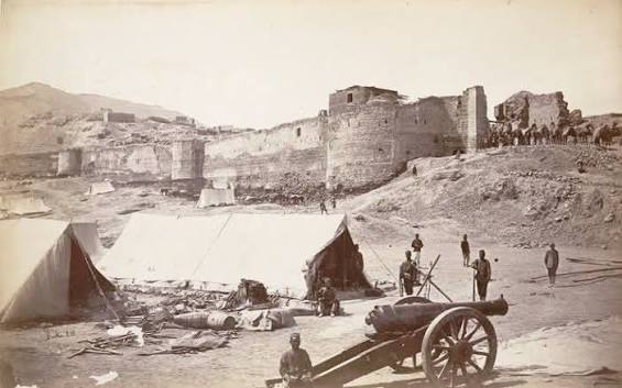 Photograph John Burke 1879, 2nd Afghan War (1878-80), with a view of the damaged Bala Hissar fortress at Kabul in Afghanistan showing soldiers posed in the foreground and camels being led into