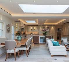 The kitchen appliances are concealed effortlessly into the white kitchen area, whereas the central island serves as a casual sitting area with storage access too. Open Kitchen With Dining Room
