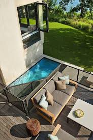 Couch With Beige And Pale Blue Cushions And A Small White Table On The Wooden Patio Of A House With An Open W Backyard Pool Small Backyard Pools Swimming Pools