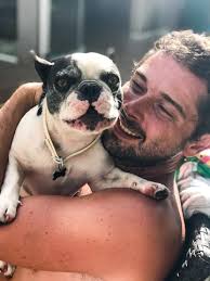 Hombre abrazando a un bulldog francés blanco y negro