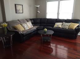 Dark finishes, such as mahogany, walnut, or cherry, stand out in sharp relief against light colors, such as a pale green or blue or a hue from the sunny side of the color wheel. Black Sectional Couch With Yellow Throw Pillows And Cherry Hardwood Floors Hardwood Floors Dark Cherry Wood Floors Living Room Colors