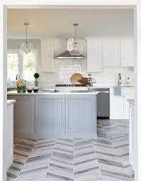 A black octagon mirror is hung over a green and gray marble floating sink vanity fitted with a matte black faucet and fixed over white and black chevron floor tiles. Gray Chevron Pattern Floor Tiles With Gray Island Transitional Kitchen
