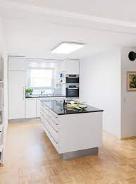 moderne weisse kuche mit edelstahlgriffen kochinsel mit dunkler arbeitsplatte und dunstabzug nach unten moderne kuche moderne weisse kuchen weisse kuche