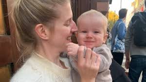 Woman holding baby outdoors.