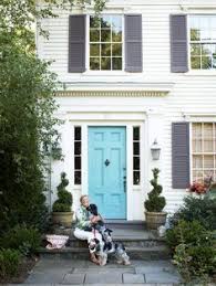 It is complemented by a chrome sconce and cream fences wrapping around the green plants. Playful Color Combination Of Turquoise Door With Purple Gray Shutters On A Very Trad House Shutter Colors White Exterior Houses Exterior Paint Colors For House
