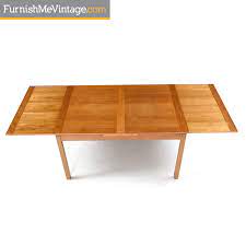 The table extends in length, the leaf folds into the table for easy storage, and the table features an umbrella hole. Vintage Danish Teak Dining Table Draw Leaf Expanding Top