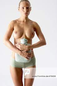 Schlanke junge Frau hält sich eine Wärmflasche an den nackten Bauch -  Weiblichkeit - Regelschmerzen, fully_released