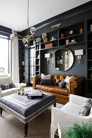Modern Black And Blue Living Room A Brass And Glass Chandelier Hangs Over A Blue Ottoman Coffee Table Placed On A Beige Rug Living Room Design Modern Living Room Interior Beautiful Living Rooms