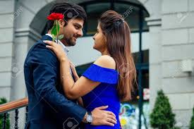 Long Haired Brunette Indian Woman In Blue Dress With Her Handsome Boyfriend  Having Dating .man Giving Rose To His Girlfriend In Summer Downtown Street  Stock Photo, Picture and Royalty Free Image. Image