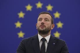 Политик произносит речь на фоне флага ЕС.