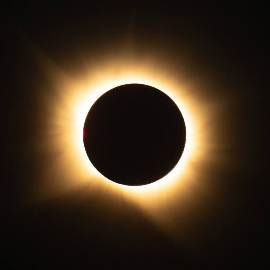 An artistic representation of a total solar eclipse, featuring the moon perfectly obscuring the sun with the solar corona visible.