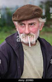 Portrait of an elderly man with a white and brown beard wearing Lederhosen  and a hat with a feather in it Stock Photo
