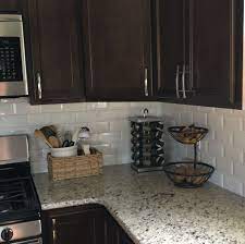 The small scale of the tiles adds a subtle texture, while a random pattern of beige, cream, and blue recalls the colors of surf and sand. Dark Cabinets White Subway Tile And Neutral Granite Backsplash Kitchen Dark Cabinets Backsplash With Dark Cabinets Dark Kitchen Cabinets