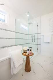 An Oval Freestanding Bathtub Sits Beside A Round Wood Accent Table And Beneath A Window Attic Apartment Attic Remodel Attic Flooring