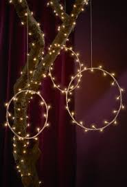 Ring Shaped Lamps And Fairy Lights Wrapped Around A Tree Branch Against A Dark Red Backdrop Gemutliche Weihnachten Ikea Weihnachten Weihnachten Im Freien