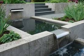 Geometrisch Uber Metallippen Fliesst Das Wasser Sachte Von Einem Quadratischen Becken Ins Nachste Wasser Im Garten Wasserspiel Garten Gartenteich
