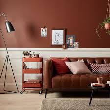 Dark Earthy Toned Walls Paired With A Leather Brown Sofa And Red Brown And Orange Accessories Living Room Colors Home Decor Brown Living Room