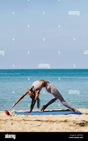 Flexible young Black woman practicing yoga and stretching outdoors by the  ocean Stock Photo - Alamy