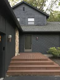 Stunning home featuring a dark brown roof, pale cream siding, real stone, white trim and warm wood doors. House Tweaking