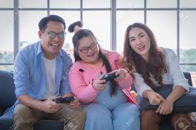 Asian Family With Down Syndrome Daughter Playing Video Game Together In  Living Room At Home For Autism Positive Family Concept. Stock Photo,  Picture and Royalty Free Image. Image 165881811.