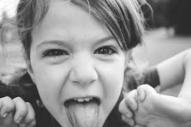 Little girl looking at the camera with her tongue out and a mocking  expression