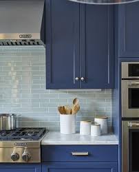 This elegant white and gray kitchen showcases modern design, from the decorative tile backsplash that runs from the marble countertops to the ceiling. Light Blue Backsplash Tiles With Blue Kitchen Cabinets Eclectic Kitchen