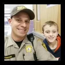 Deputy Wade Thomas makes a new friend at Pioneer Elementary School during  the Suffolk Sheriff's office D.O.T.S.S. (Deputies Outreach to Students and  Staff) program.