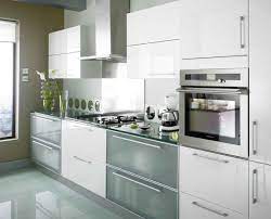 This sleek modern kitchen features shiny white countertops, custom wood cabinets, and a stone floor. Pin On White Kitchens