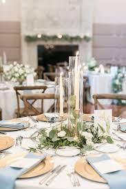 Elegant Simplicity In This Reception Centerpiece Of Eucalyptus And Olive Leaf Greenery Nestled Within A Round Wedding Tables Wedding Table Wedding Centerpieces