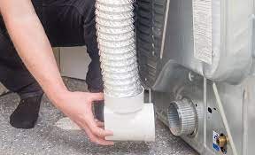 A Person Reconnects The Venting Duct To The Back Of A Clothes Dryer Dryer Vent Dryer Vent Brush How To Clean A Dryer Vent