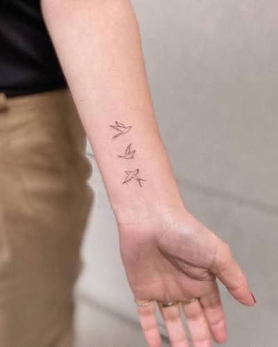 Fine line style flying birds tattoo located on the