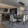 Stylish dining room showcases beige chairs and a gray curved dining table fixed to the marble pillar that's lined with hanging glass pendants. 1