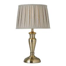 Still life side view of antique lamp with hanging shade and brass base on top of small wood and brass table in room lamp, table lamp, brass with candle lamps, classic, elegant, retro style. Oslo Antique Brass Finish Medium Table Lamp Base Only Oslo M An Tiffany Lighting Direct