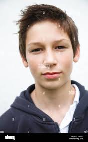 Portrait of teenage boy looking straight at camera informal clothes brown  hair white wall background Stock Photo