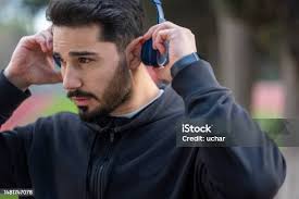 Candid Shot Of Stylish Guy Listening To Contemporary Music Using His  Headphones Walking In The Misty Park Of The City Street Fashion Style  People Lifestyle And Technology Concept Copy Space Stock Photo -