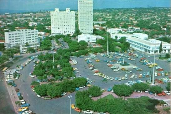 Praça Cívica, anos 80. 🌈🚗 Do alto, Goiânia parecia pulsar em cores. Os  carros espalhados pela praça — amarelos, azuis, vermelhos, verdes —  transformavam o coração da capital em um verdadeiro retrato