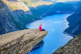 More than 2,000 feet above, a hiker is perched atop trolltunga, a cliff that juts. The Girl Sits On The Edge Of The Cliff On The Trolltunga Norway Stock Photo Picture And Royalty Free Image Image 137458292