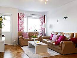 Simple living room design with extra touches that make it noteworthy such as dark green drapes, lamps on antique round wood tables in the corners and matching gold/green sofas. Living Room Ideas House N Decor